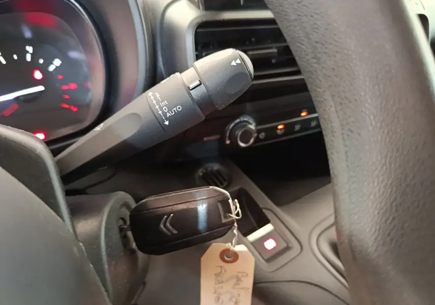 Gros plan intérieur sur le volant et la clé de contact d’un Citroën Berlingo blanc, avec tableau de bord partiellement visible.
