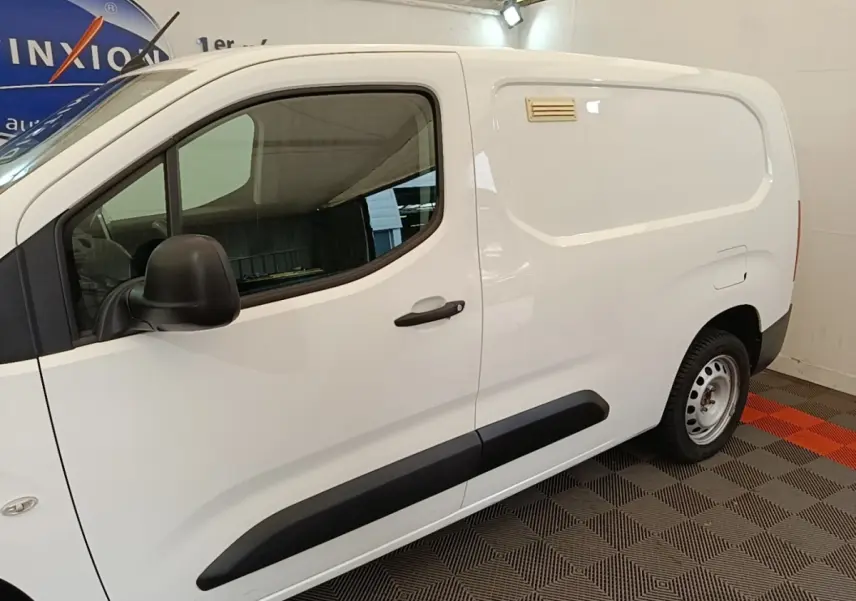 Vue de profil côté gauche d’un Citroën Berlingo XL blanc avec protections latérales noires et jante acier simple.