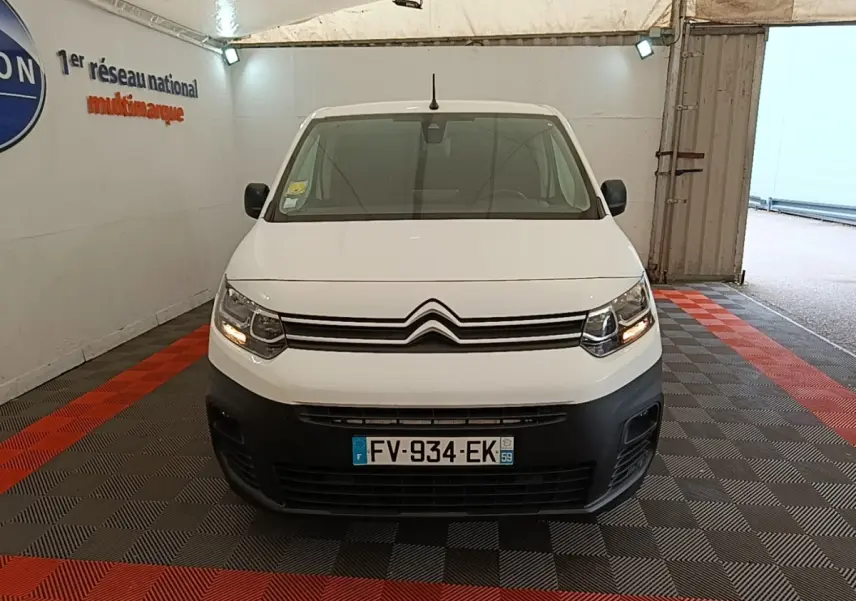 Vue de face d'un Citroën Berlingo XL blanc avec pare-chocs noir et feux allumés dans un garage.