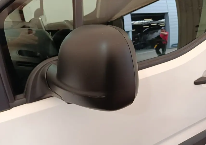 Rétroviseur noir côté gauche d’un Citroën Berlingo XL blanc, vue rapprochée sur la porte avant.