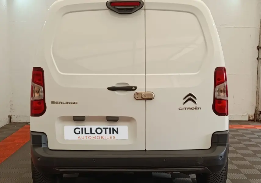 Vue arrière d’un Citroën Berlingo blanc de 2020 avec portes battantes et logo visible sur fond d’atelier.