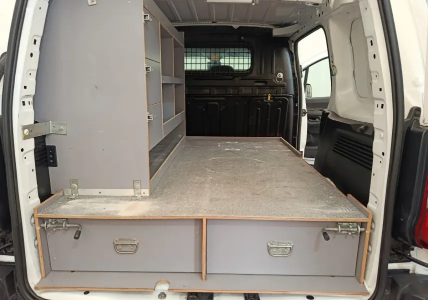Vue arrière ouverte du Citroën Berlingo blanc, montrant l'aménagement intérieur avec étagères et plateau de rangement gris.