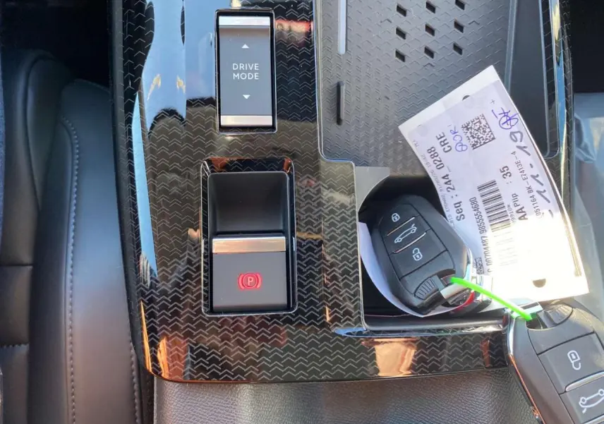 Gros plan sur la console centrale noire du Citroën C5 Aircross 2026 avec boutons Drive Mode et frein à main électronique.