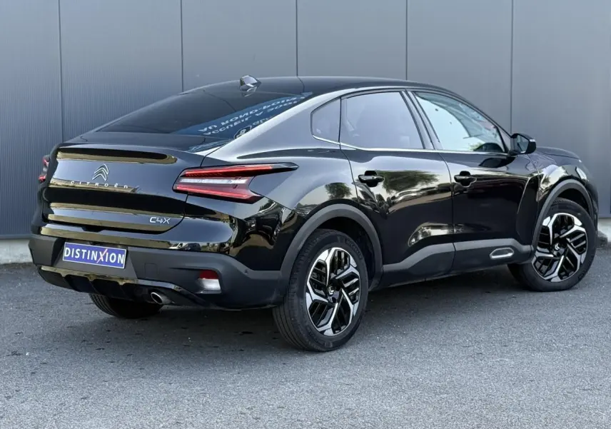 Vue 3/4 arrière droite de la Citroën C4 X noire Perla avec jantes alliage et feux LED en V distinctifs.