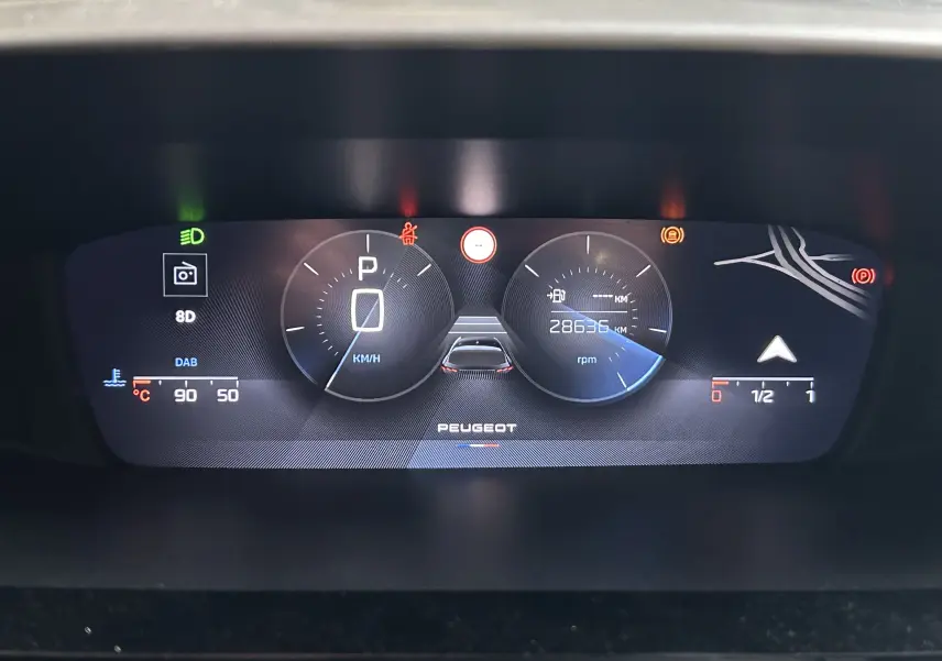 Tableau de bord numérique de Peugeot 308 rouge 2024, affichant vitesse, kilométrage et indicateurs divers.