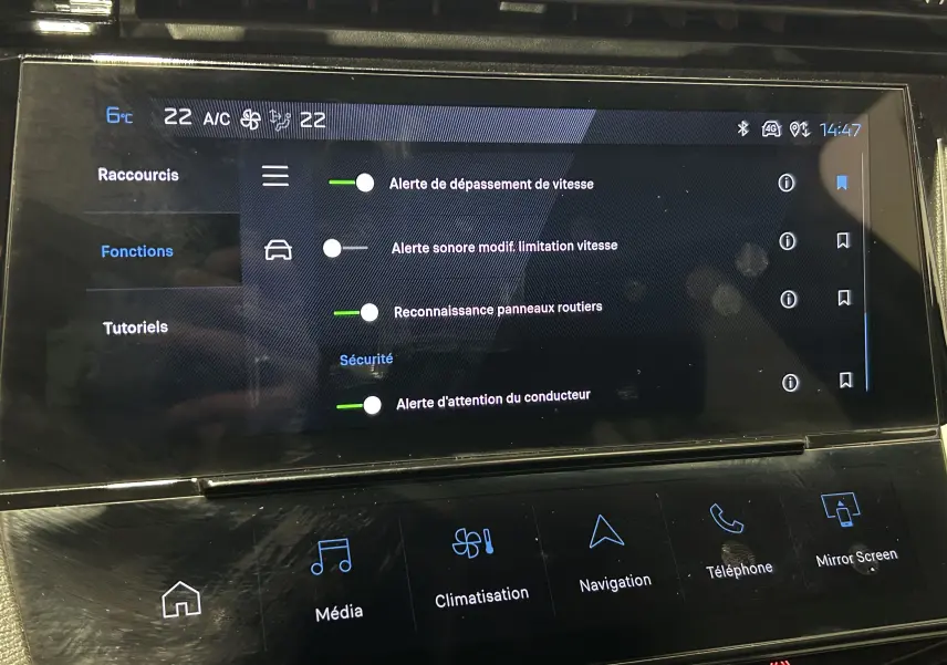 Écran tactile central de la Peugeot 308 rouge 2024 montrant les réglages d’alertes de sécurité et climatisation.