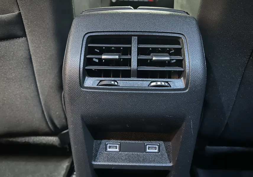 Vue rapprochée de la console arrière noire avec bouches d’aération et deux ports USB de la Peugeot 308 rouge 2024.