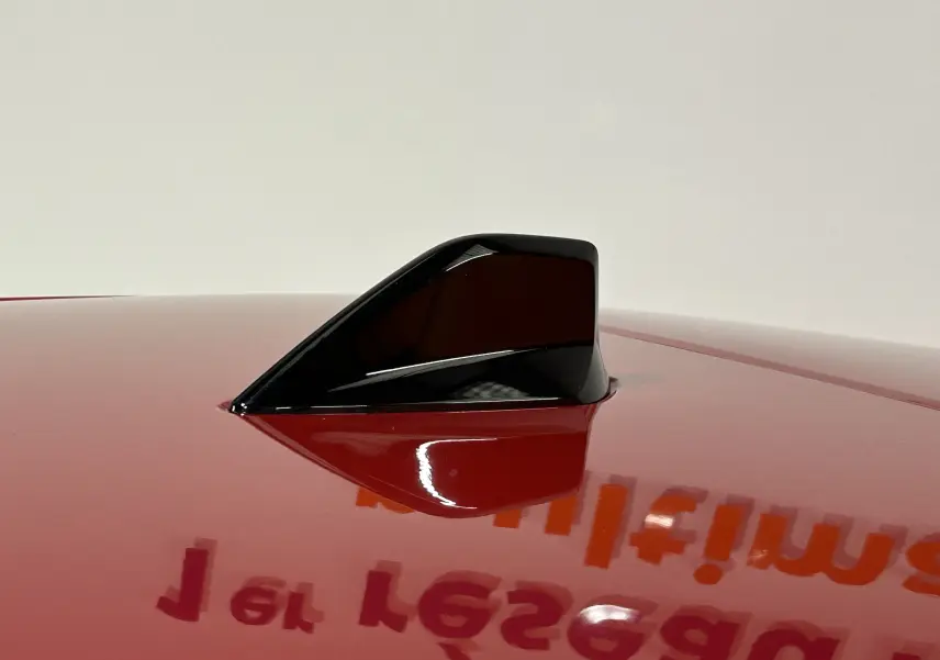Antenne requin noire sur le toit rouge brillant d'une Peugeot 308 2024 vue en gros plan.