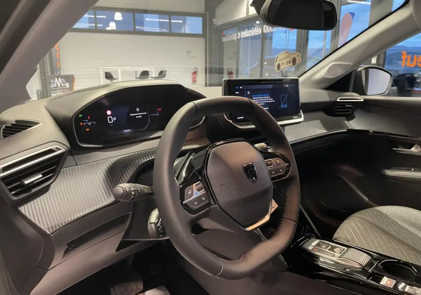 Vue intérieure avant droite du Peugeot 208 1.2i Hybrid 2025 avec tableau de bord numérique et volant compact cuir.