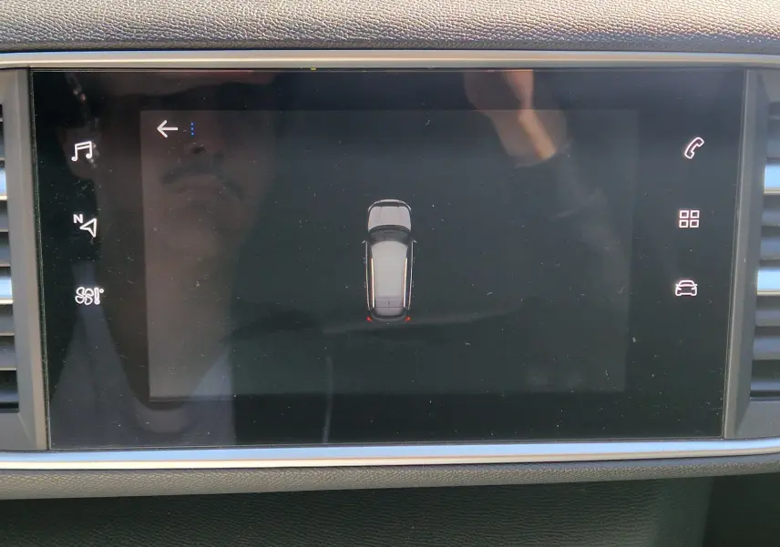 Écran tactile intérieur montrant la vue de dessus du véhicule noir Peugeot 308 SW, avec icônes de contrôle autour.