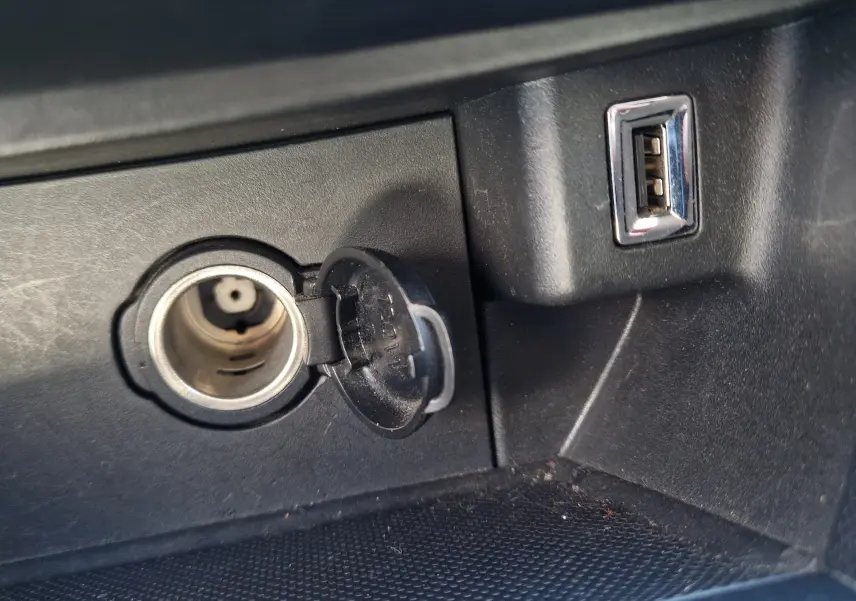 Prise allume-cigare ouverte et port USB visibles dans l'habitacle noir du Peugeot 308 SW 2021.