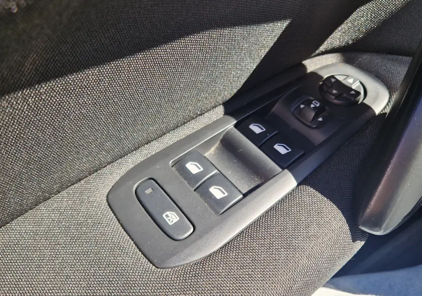 Gros plan sur les commandes de lève-vitres et rétroviseurs côté conducteur d'une Peugeot 308 SW noire de 2021.