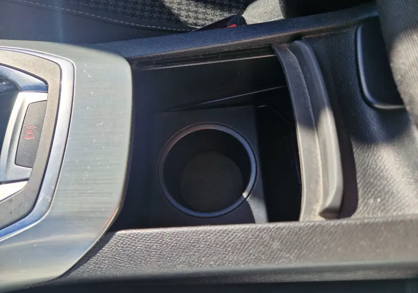 Gros plan sur le porte-gobelet central et la commande de frein à main électrique dans l'habitacle du Peugeot 308 SW noir.