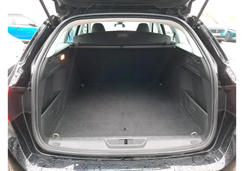 Coffre ouvert vu de l'arrière d'une Peugeot 308 SW noire, montrant un espace de chargement vide et propre.