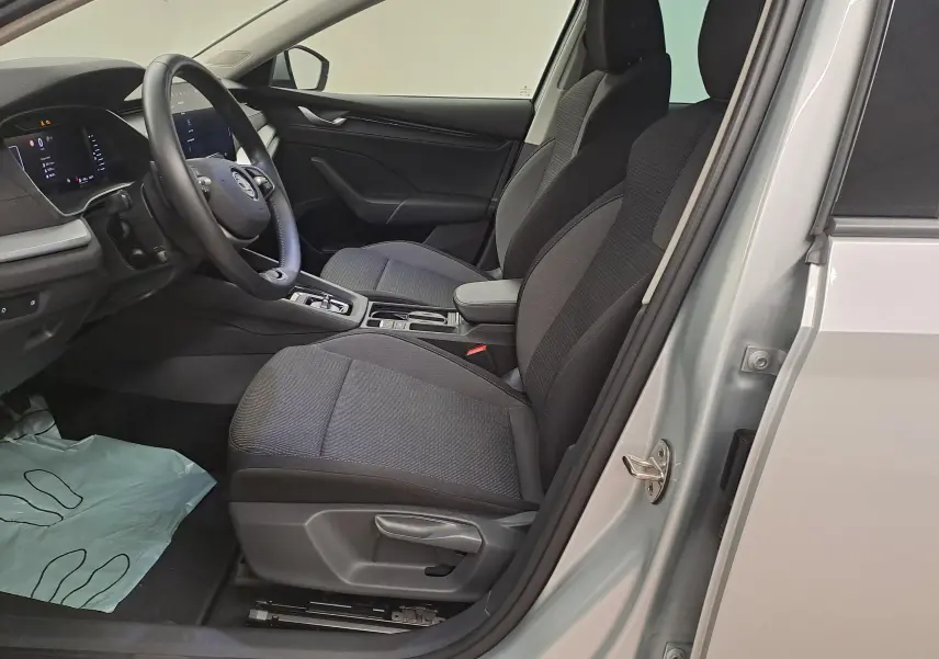 Vue intérieure côté conducteur de la Skoda Octavia Combi gris argent 2025, sièges tissu noir et tableau de bord moderne.