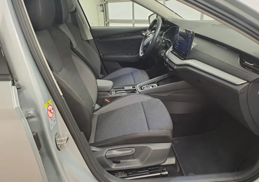 Vue intérieure côté conducteur de la Skoda Octavia Combi gris argent 2025, avec sièges tissu et écran tactile central.
