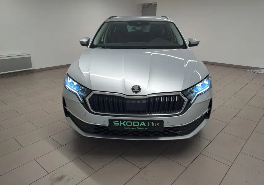 Vue frontale d'une Skoda Octavia Combi 2025 gris argent avec phares allumés et calandre noire distinctive.
