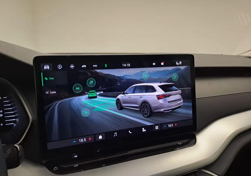 Écran tactile intérieur montrant une Skoda Octavia Combi gris argent en 3/4 arrière sur route sinueuse montagneuse.