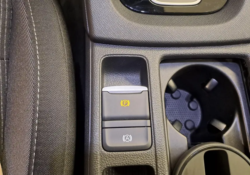Gros plan sur la console centrale de la Skoda Octavia Combi 2025, boutons frein à main électronique et auto hold visibles.