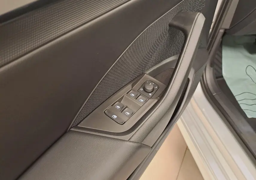 Gros plan sur la portière avant gauche gris argent d'une Skoda Octavia Combi 2025, avec commandes des vitres et réglage des rétroviseurs.