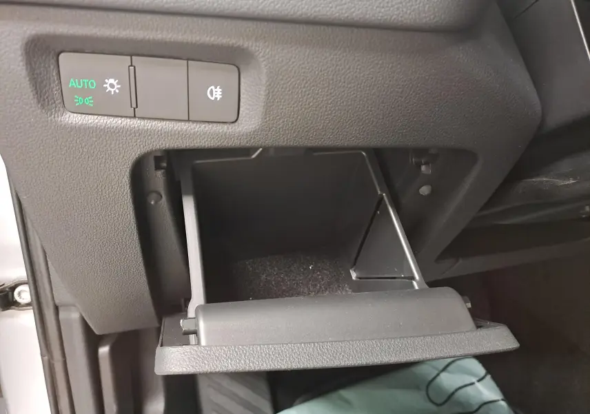 Gros plan sur le rangement ouvert côté conducteur du Skoda Octavia Combi gris argent, avec commandes d'éclairage visibles.