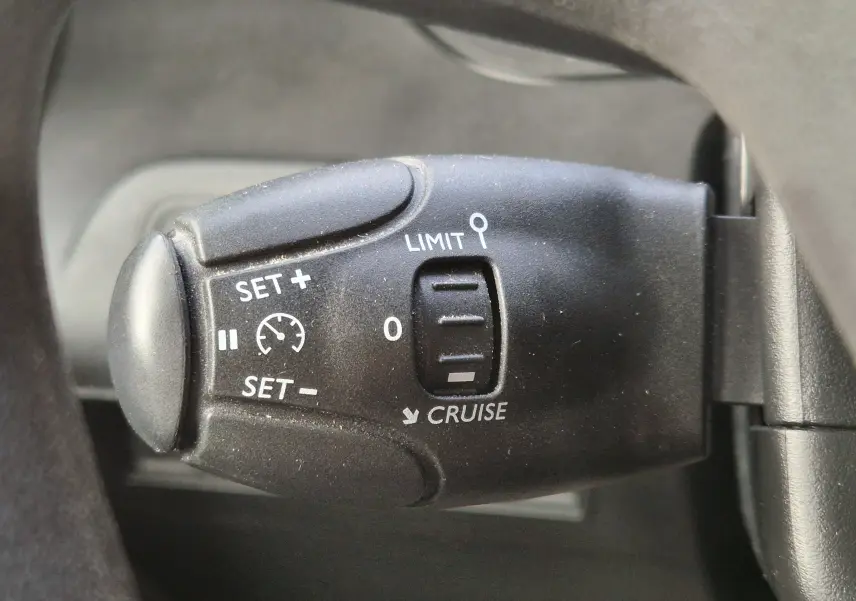 Gros plan sur la commande de régulateur de vitesse noire du Peugeot Partner Long 2021, avec inscriptions blanches visibles.