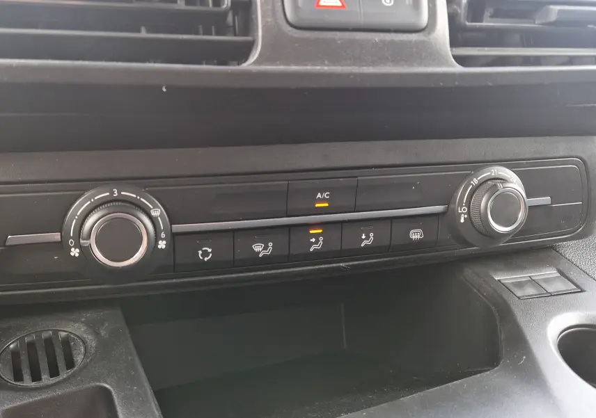 Gros plan sur la console centrale du Peugeot Partner blanc 2021, montrant les commandes de climatisation et ventilation.