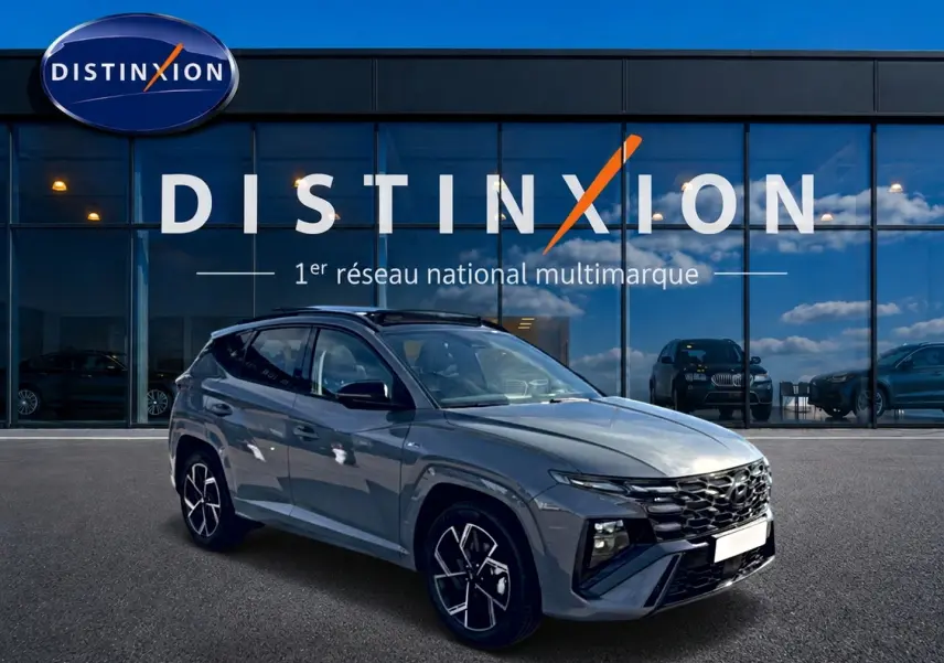Hyundai Tucson 2026 gris shadow en 3/4 avant droit, avec calandre noire et jantes alu distinctives.
