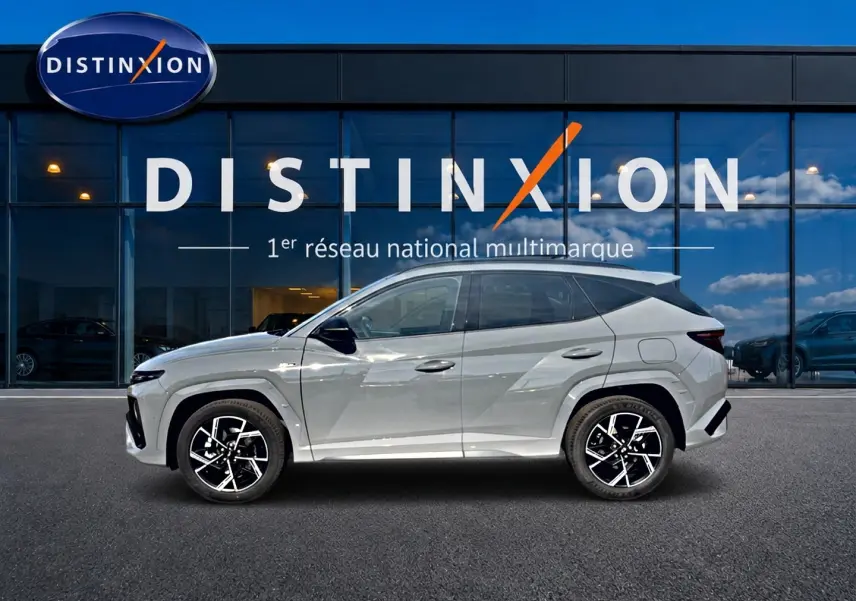 Vue latérale gauche du Hyundai Tucson gris shadow 2026 avec jantes alu noires et toit panoramique visible.
