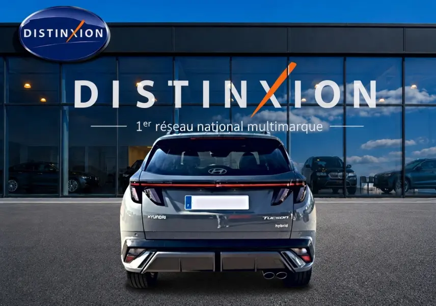 Vue arrière d'un Hyundai Tucson gris shadow 2026 hybride, avec feux arrière LED et double sortie d'échappement visible.