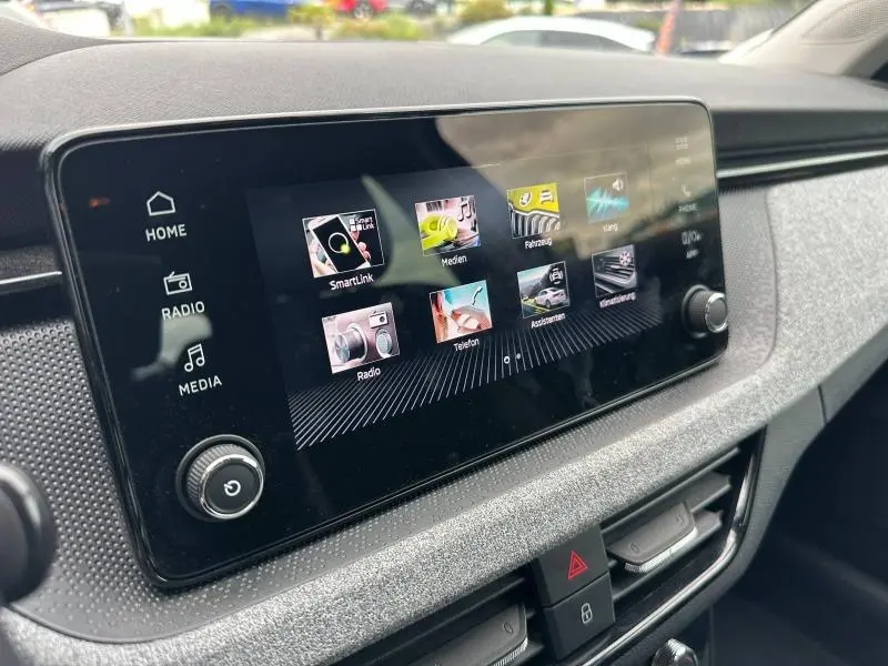 Écran tactile central en gros plan dans l’habitacle gris d’une Skoda Scala 2025, avec commandes multimédia visibles.