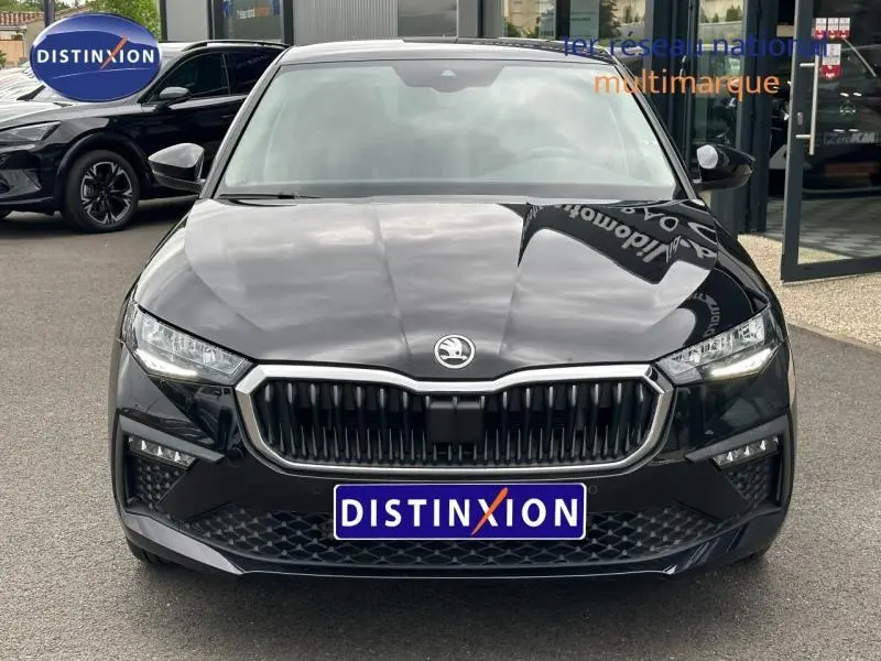Vue avant d'une Skoda Scala 2025 noir Magic nacré avec calandre chromée et phares LED allumés.