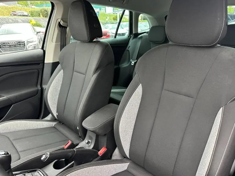Vue intérieure des sièges avant tissu noir et gris de la Skoda Scala 2025, avec accoudoir central et ceintures visibles.