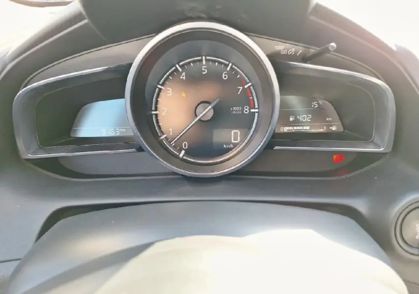 Vue rapprochée du tableau de bord de la Mazda2 2023, affichant le compte-tours central et l'ordinateur de bord.