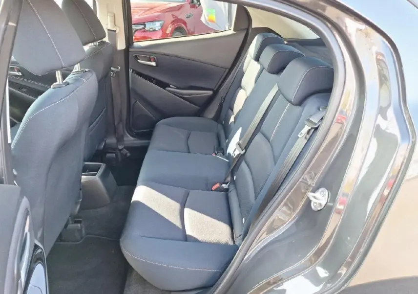 Vue côté gauche arrière sur les sièges arrière gris foncé de la Mazda2 2023 avec portes ouvertes.