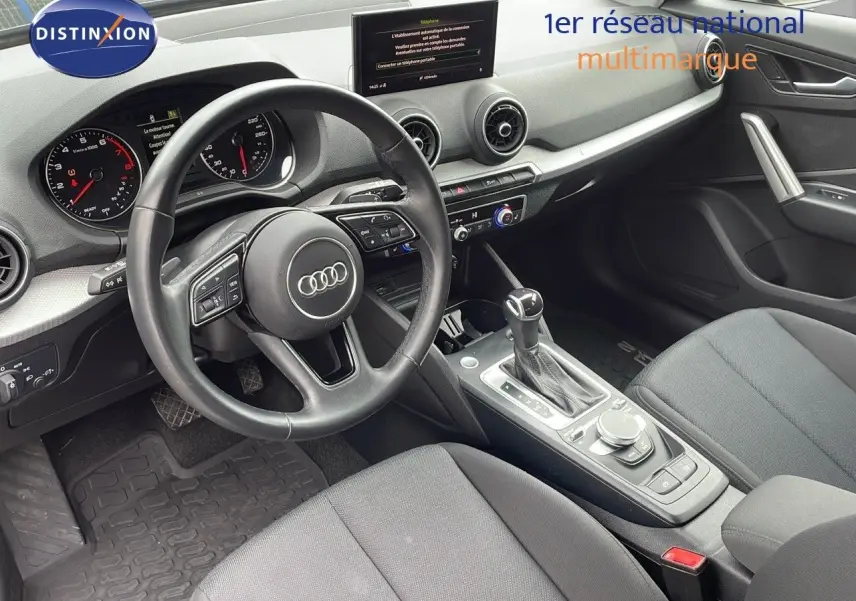 Intérieur de l'Audi Q2 35 TFSI 2023 vu côté conducteur, avec volant multifonction et console centrale moderne.