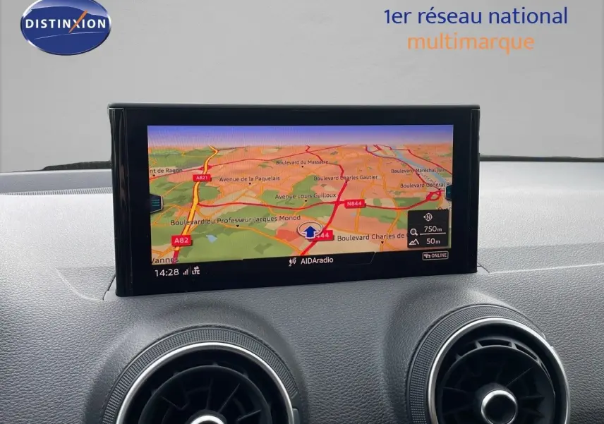Vue rapprochée de l'écran GPS et des aérateurs ronds du tableau de bord d'un Audi Q2 noir mito metal 2023.