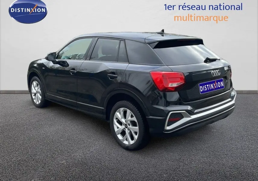 Audi Q2 noir mito metal vue 3/4 arrière côté droit, avec jantes argentées et feux arrière rouges visibles.
