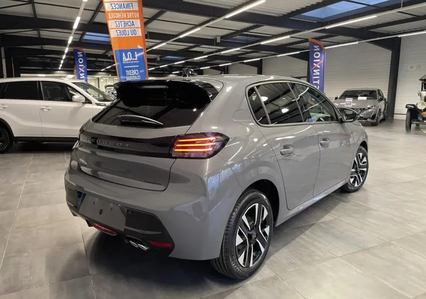 Peugeot 208 gris Selenium vue 3/4 arrière droit en intérieur avec jantes alliage bi-tons et feux LED allumés.