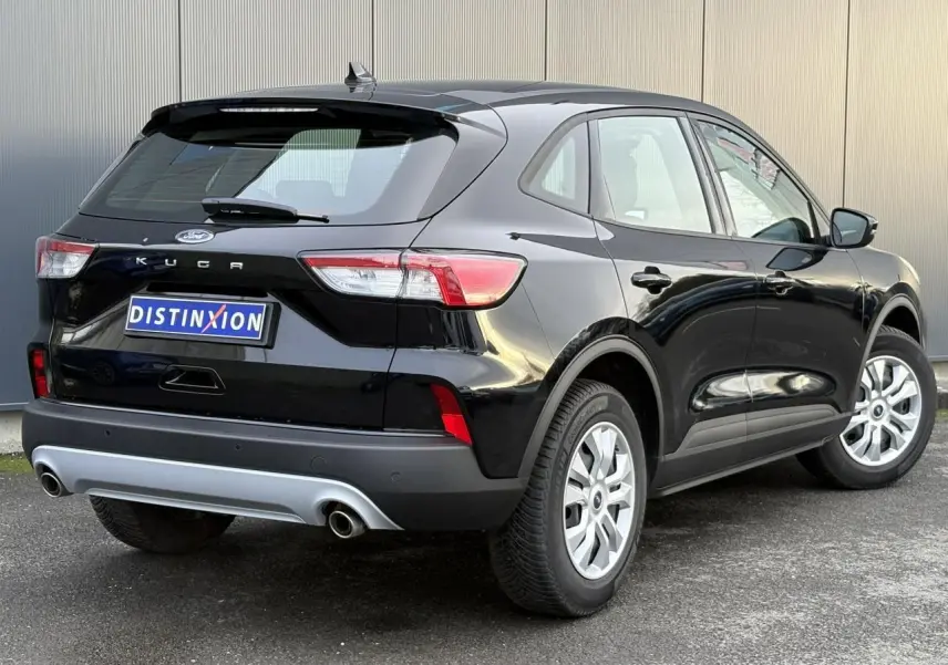 Vue 3/4 arrière droite d'un Ford Kuga 2024 noir Obsidien avec double sortie d'échappement et jantes argentées.