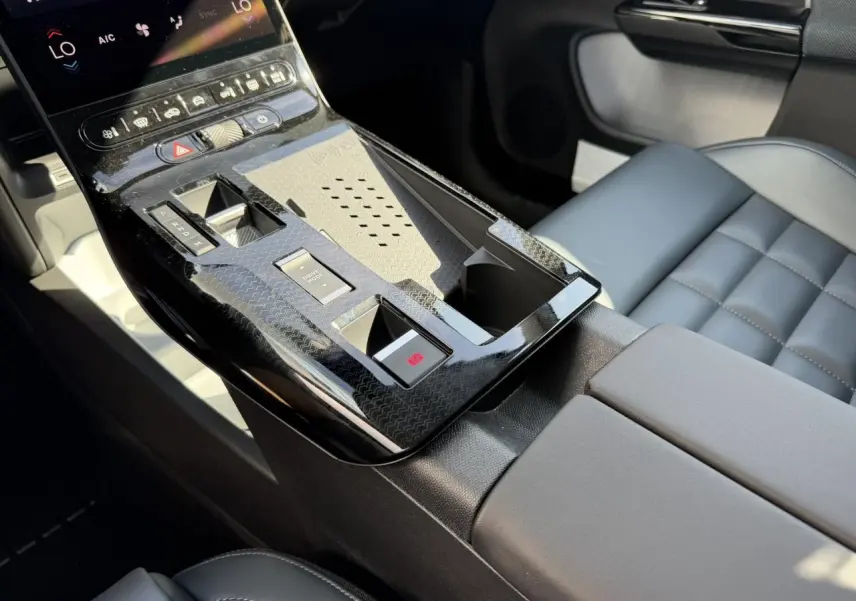 Vue rapprochée de la console centrale noire brillante et des sièges gris du Citroën C5 Aircross hybride 2026.
