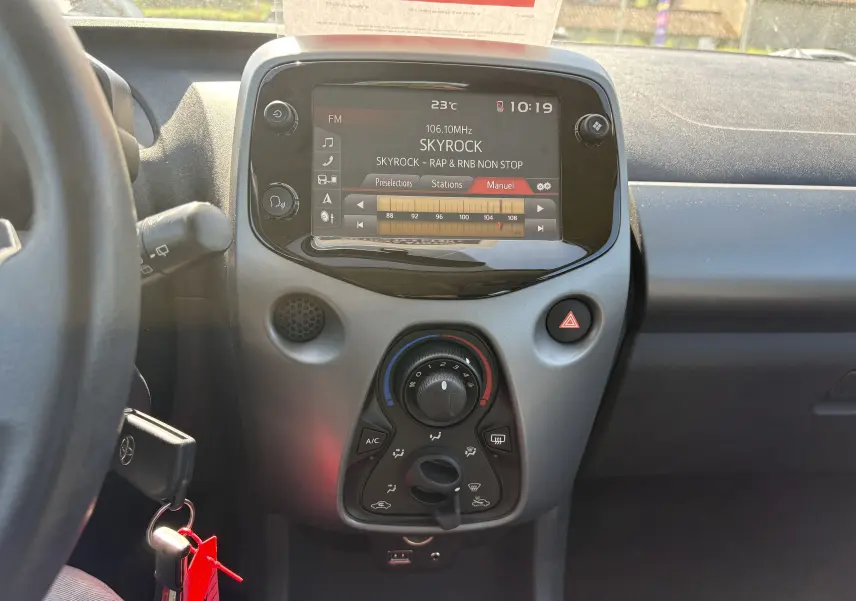 Vue intérieure centrée sur la console centrale de la Toyota Aygo MC 2020, avec écran tactile et commandes climatisation visibles.