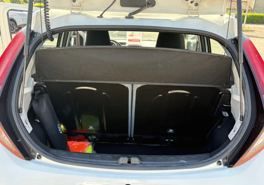 Vue arrière ouverte du coffre blanc d'une Toyota Aygo MC 2020, avec cache-bagages et accessoires visibles.