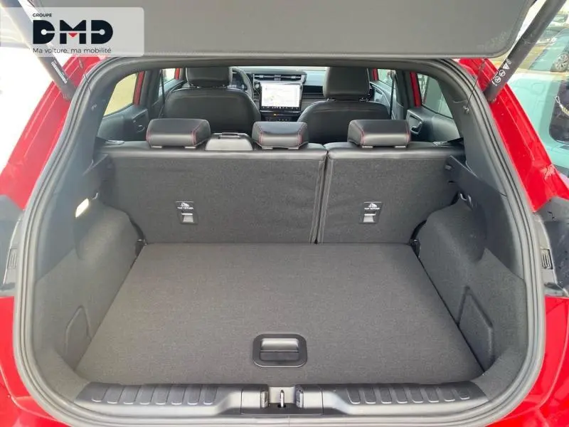 Coffre ouvert vu de l'arrière d'un Ford Puma rouge, montrant l'espace de chargement et les sièges arrière rabattus.