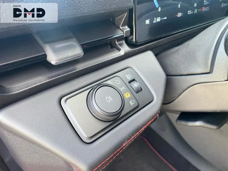 Gros plan sur le bouton de commande des phares dans l'habitacle du Ford Puma rouge, avec surpiqûres rouges visibles.