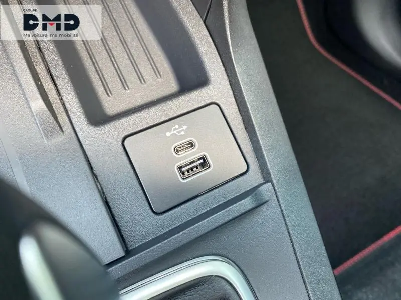 Prise USB Type-C et USB-A en gros plan sur la console centrale noire avec surpiqûres rouges du Ford Puma rouge.