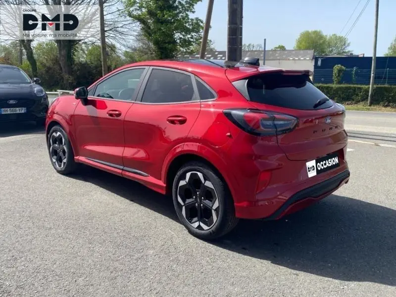 Ford Puma rouge métallisé vu en 3/4 arrière droit, avec jantes alu noires et vitres arrière surteintées.