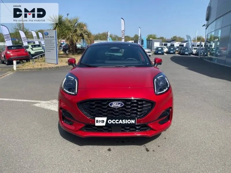 Vue avant frontale d'un Ford Puma rouge métallisé avec calandre noire et phares LED distinctifs, sur parking extérieur.