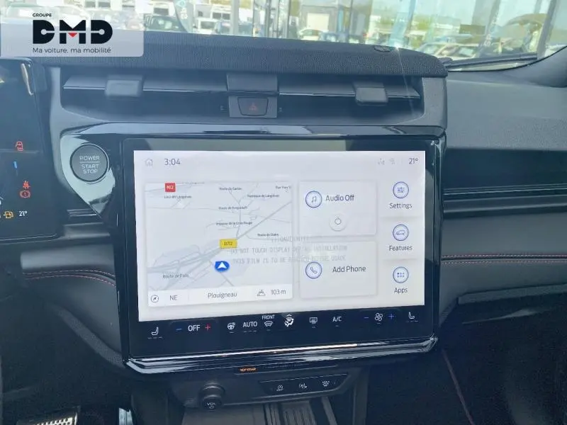 Vue rapprochée de l’écran tactile central du Ford Puma rouge, affichant la navigation GPS et commandes multimédia.