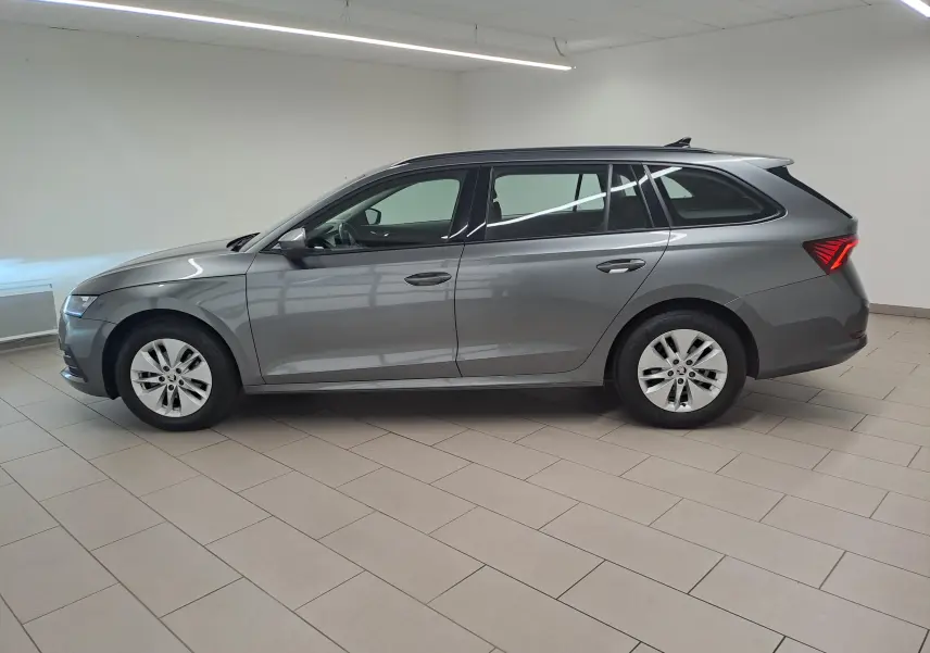 Vue de profil côté gauche d'une Skoda Octavia Combi 2024 en gris graphite métallisé dans un intérieur lumineux.